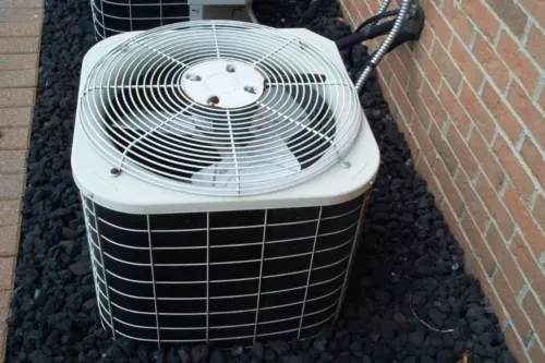 An AC unit is on top of black rocks after a new installation.
