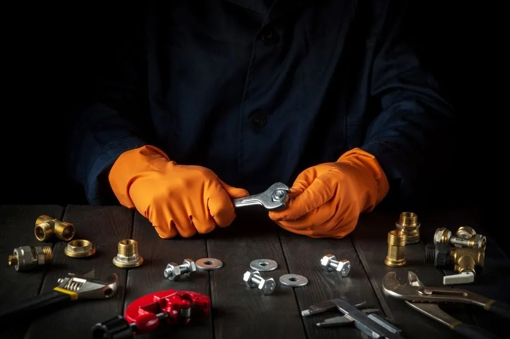 An HVAC expert with orange gloves assembles parts for a heater replacement.