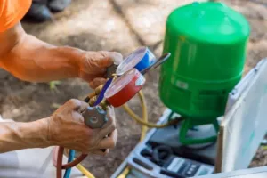 An HVAC professional repairs an AC air compressor for a client.