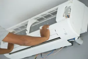 An AC repair specialist attaches a cover to a new unit after installation.