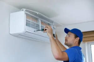 An AC repairman working on a ductless mini split system repair.