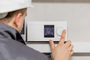 An HVAC technician installs a new thermostat for a client.