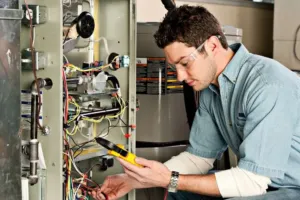 An HVAC technician repairing the electrical components of a furnace.